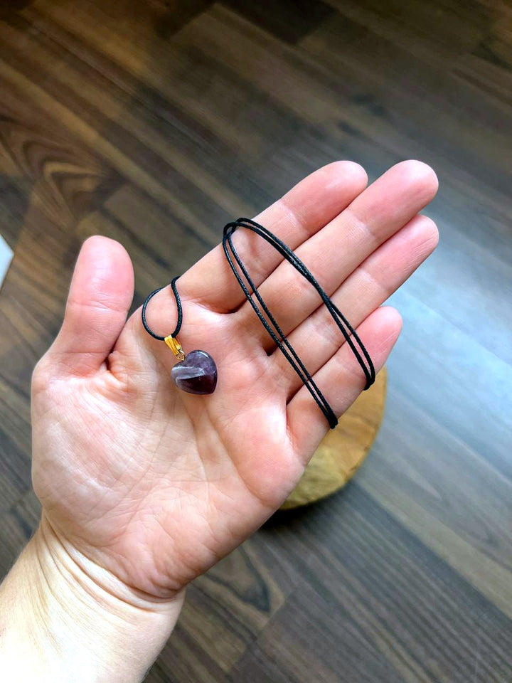 Amethyst Herz Anhänger mit schwarzem Baumwollband auf der Hand