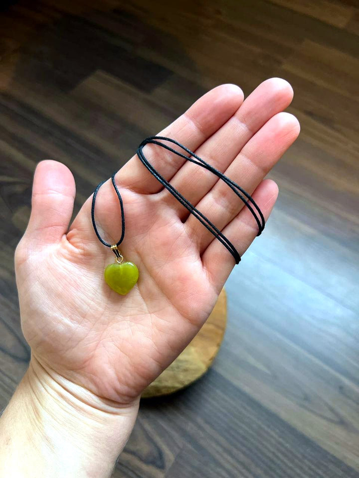 Jade Serpentin Herz Anhänger mit schwarzem Baumwollband auf der Hand