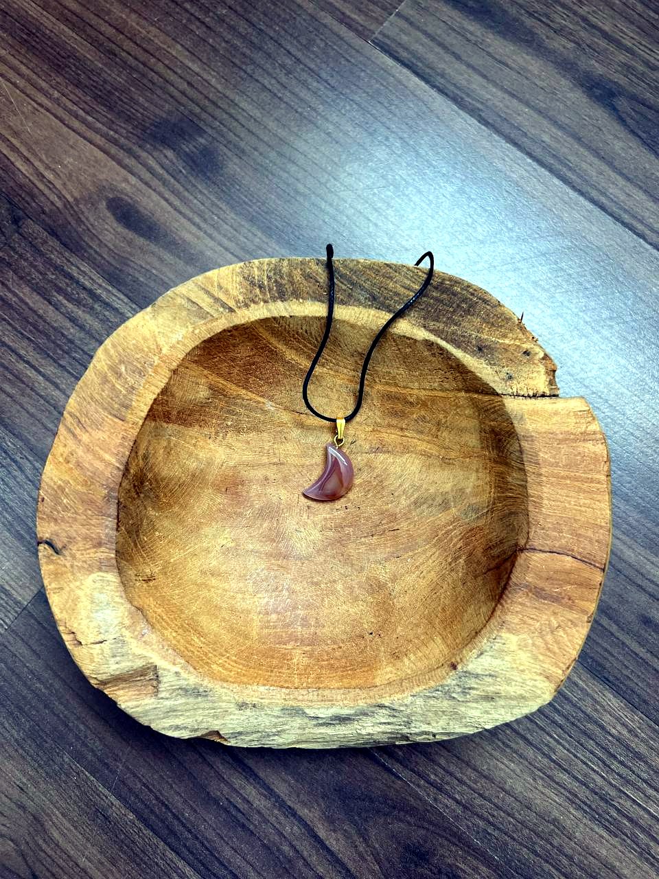 Oranger Achat Mond Anhänger mit goldener Öse in einer Holzschale