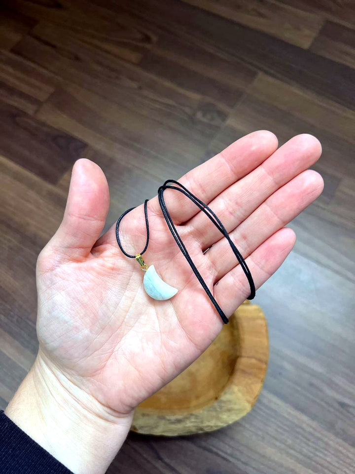 Aquamarin Mond Anhänger mit schwarzem Baumwollband auf der Hand