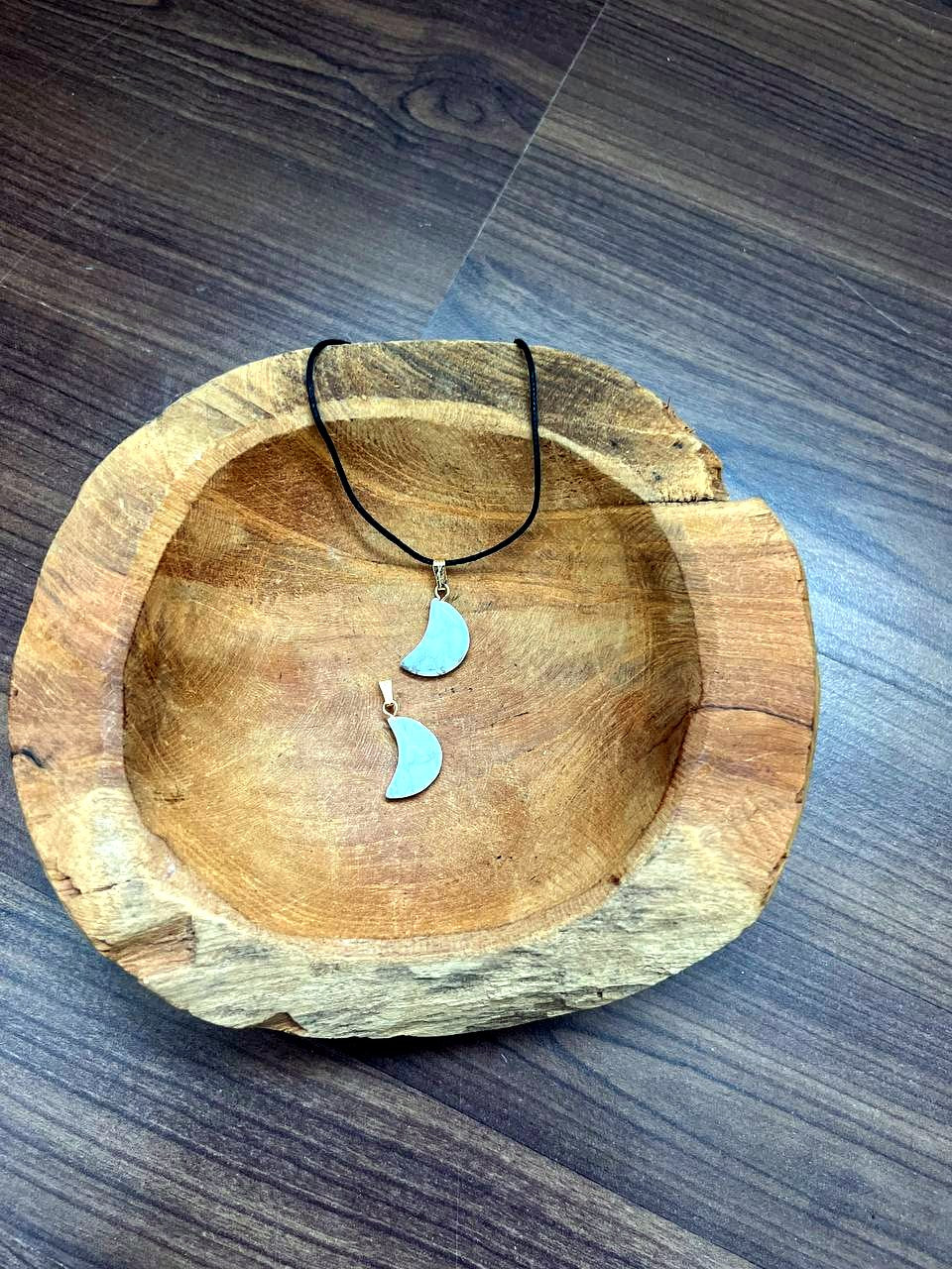 Magnesit Mond Anhänger mit goldener Öse in einer Holzschale