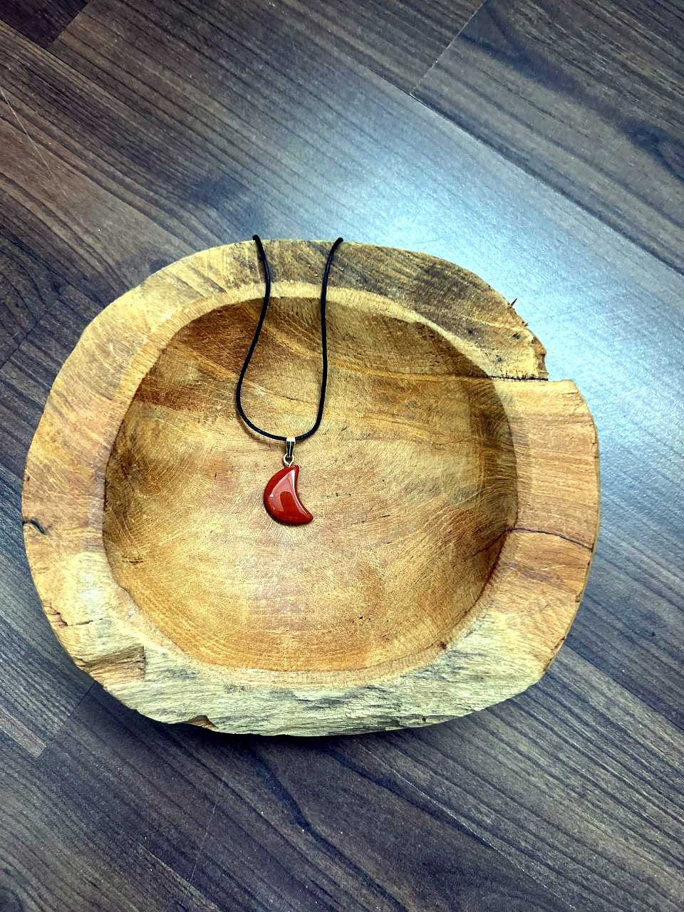 Roter Jaspis Mond Anhänger mit goldener Öse in einer Holzschale