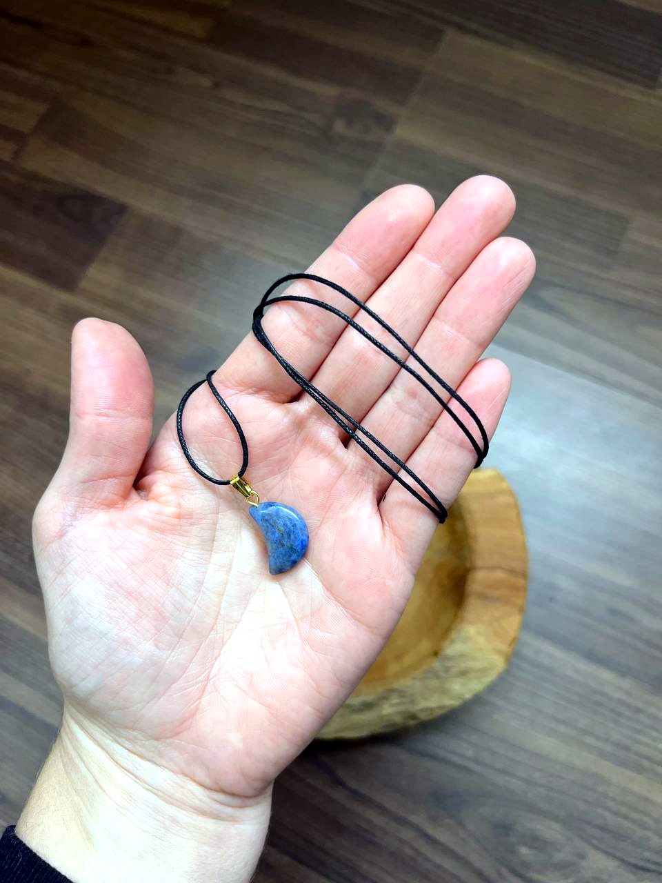 Sodalith Mond Anhänger mit schwarzem Baumwollband auf der Hand