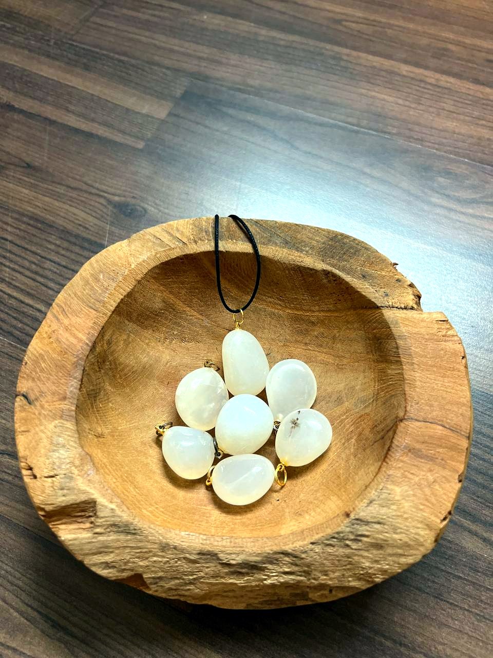 Weiße Achat Trommelstein Anhänger in einer Holzschale