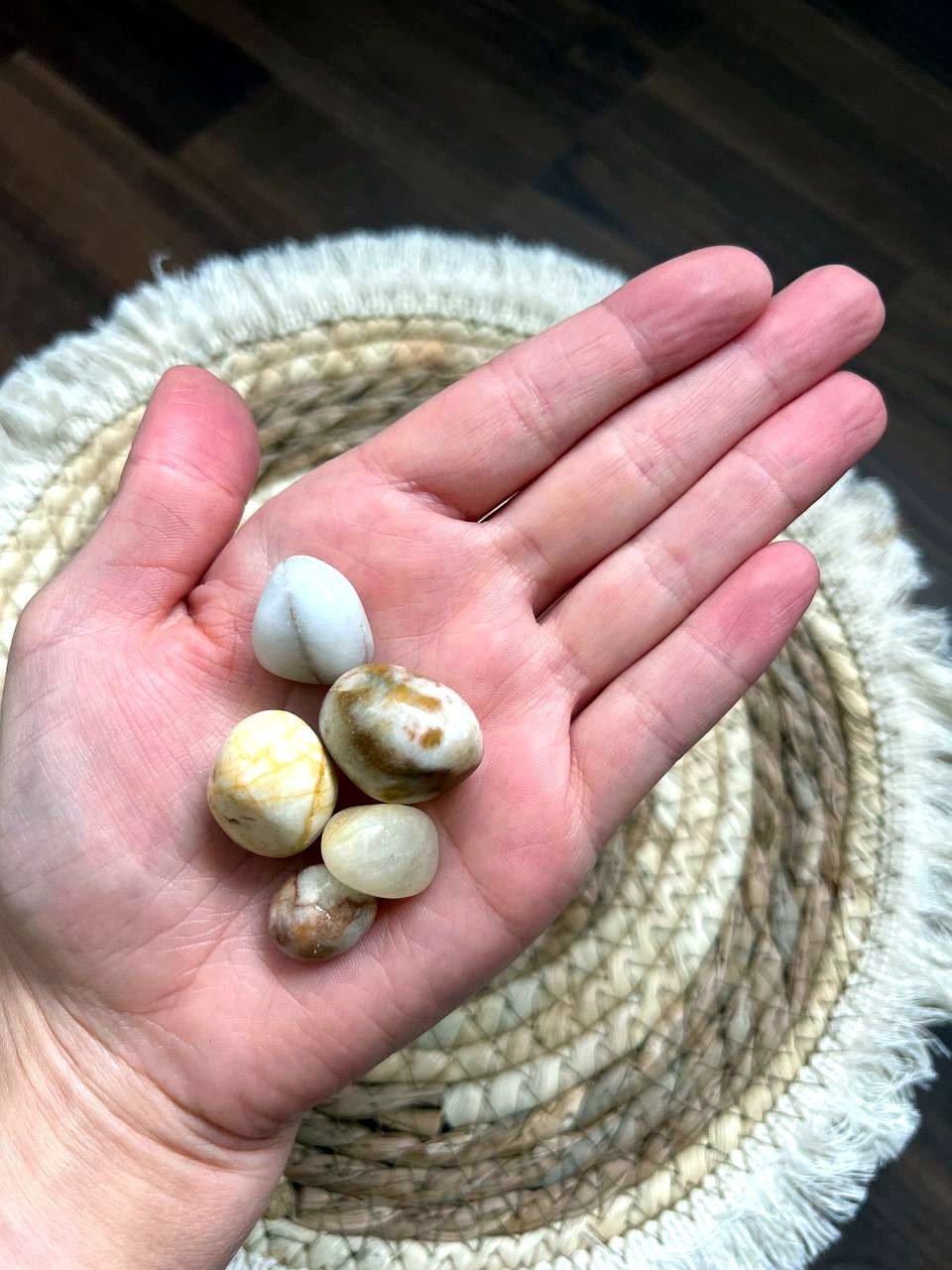 Cremeweiße Trommelsteine auf der Hand