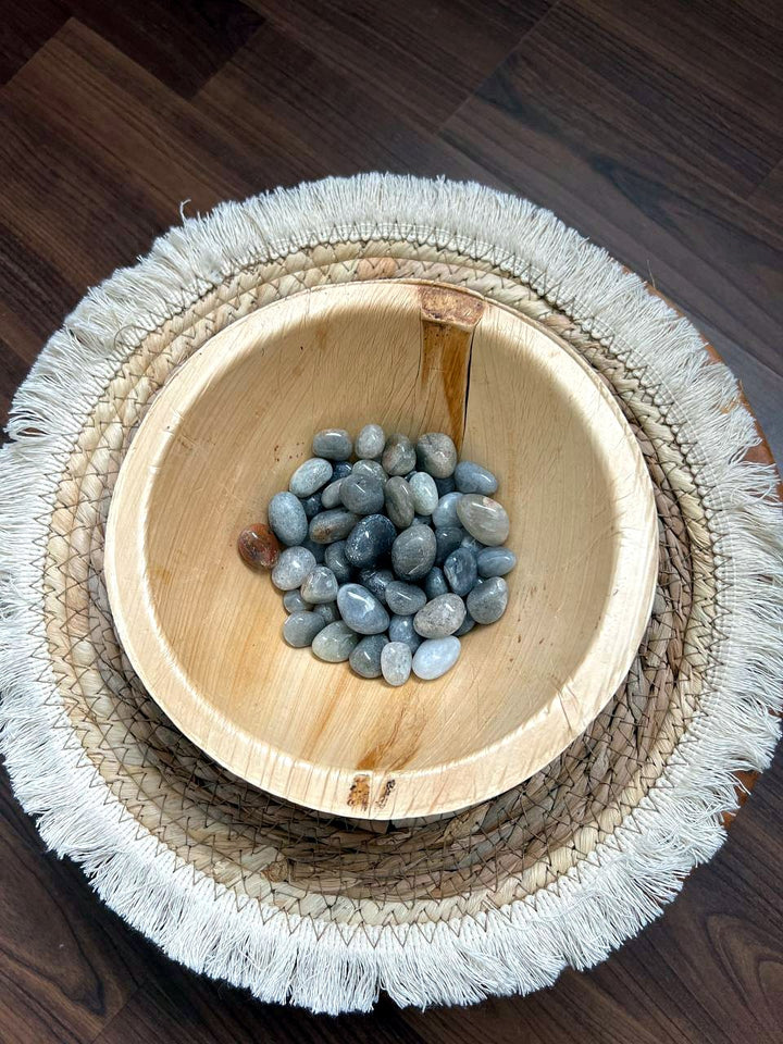 Grau-blaue Trommelsteine in einer Holzschale