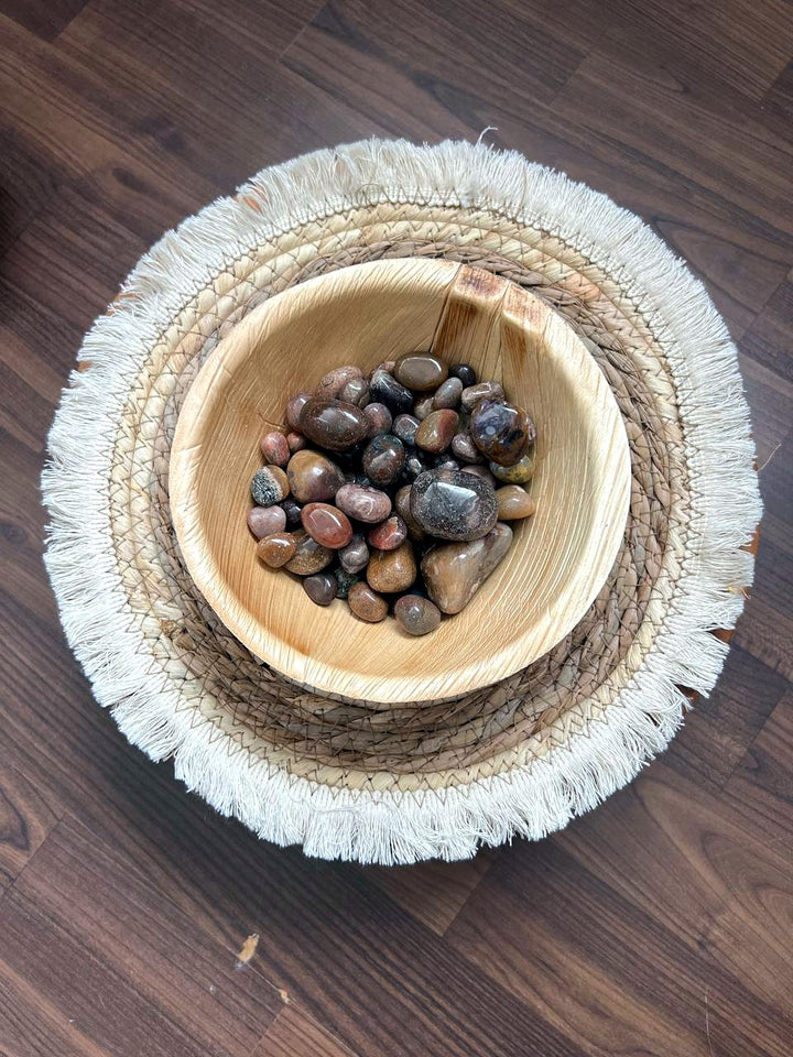 Braune und roséfarbene Trommelsteine in einer Holzschale
